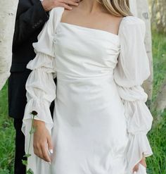 a woman in a white dress standing next to a man