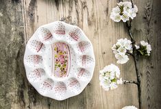 a white plate sitting on top of a wooden table next to some flowers and branches