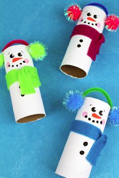 three snowmen made out of toilet paper tubes with pom - poms on them