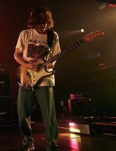 a man standing on top of a stage holding a guitar