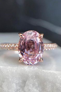 a pink diamond ring sitting on top of a rock