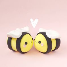 two yellow and black bees with hearts on their heads are facing each other in front of a pink background