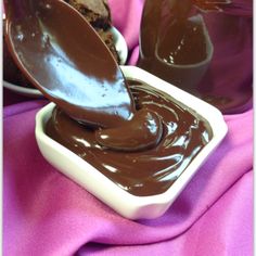 a spoon full of melted chocolate on top of a white bowl