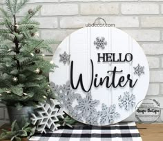 a wooden sign that says hello winter next to a christmas tree and snowflakes