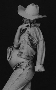 black and white photograph of a pregnant woman wearing a cowboy hat with her hands on her hips