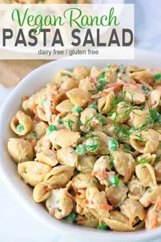 a white bowl filled with pasta salad and topped with green onions, carrots and parsley