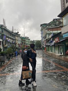 two people walking down the street in the rain