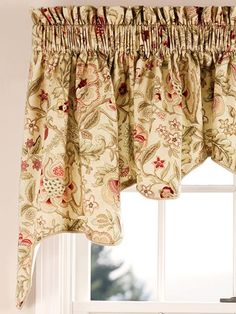 a window with a flowered valance hanging from it's side, next to a window sill