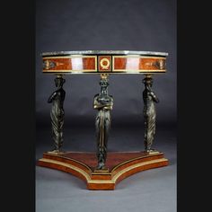 an ornately decorated table with two statues on it's sides and a marble top