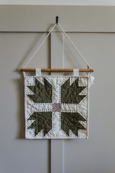 a green and white wall hanging with an arrow design on the front, along with two wooden pegs