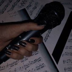 a woman's hand holding a microphone over sheet music