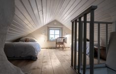 an attic bedroom with wooden floors and white walls, along with a bed in the corner