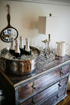 an ice bucket filled with wine glasses on top of a dresser