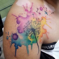 a watercolor tattoo with a dandelion painted on it's back shoulder