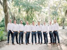 a group of men standing next to each other in front of trees and dirt ground