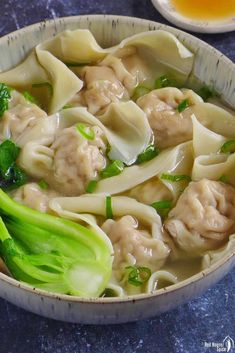 a bowl filled with dumplings and broccoli on top of a blue counter