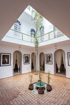 an indoor courtyard with potted plants and pictures on the wall