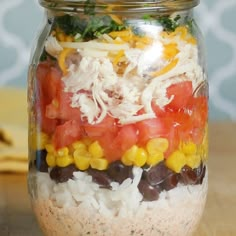 a mason jar filled with rice, beans, tomatoes and other vegtables