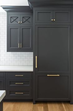 a kitchen with black cabinets and gold handles