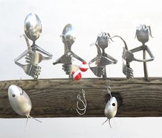 several metal figurines are hanging on a wooden pole with fishing hooks attached to them