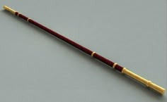 a red and gold colored cane on a gray background