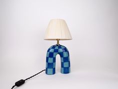 a lamp with a blue checkered design on it and a black cord attached to the base