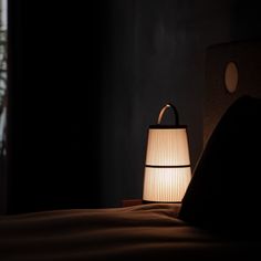 a lamp that is sitting on top of a bed in the dark, next to a window