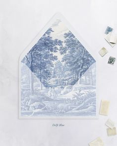 a blue and white envelope with some stamps on it next to an envelope that has a drawing of a house in the woods