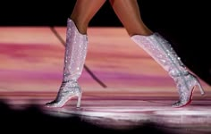 the legs and boots of a woman in high heeled shoes are shown on stage