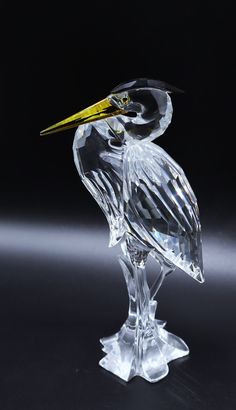 a glass bird sitting on top of a clear table next to a black background,