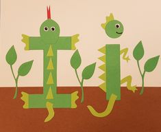 a paper cut out of the letter j with two plants and a lizard on it