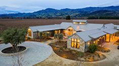 an aerial view of a home in the middle of a field with mountains in the background