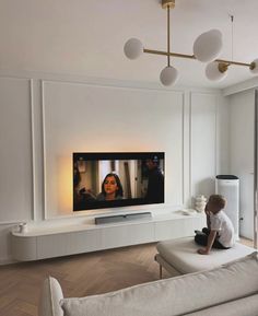 a person sitting on a couch in front of a flat screen tv that is mounted to the wall