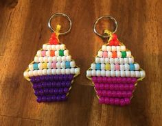 two key chains made to look like cupcakes on a wooden table with beads