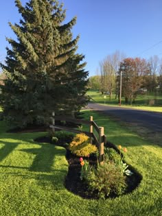 a wooden fence in the middle of a green lawn with flowers and trees around it