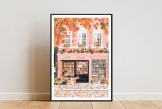 an art print of a coffee shop with autumn leaves on the window and chairs in front