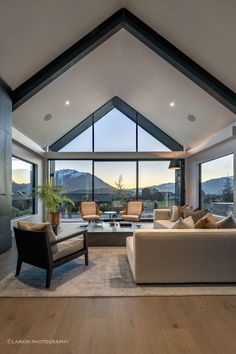 a living room filled with lots of furniture next to large windows and a wooden floor