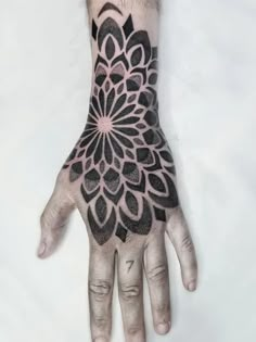 a person's hand with a black and white tattoo design on the left palm