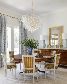 a dining room table with four chairs and a chandelier hanging from the ceiling