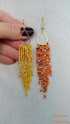 a pair of yellow and orange beaded earrings on a person's left hand