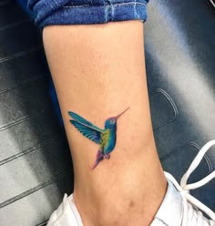 a small colorful hummingbird tattoo on the side of a woman's right leg