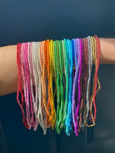 a person's arm with many different colored bracelets on top of each other