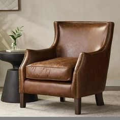 a brown leather chair sitting next to a table with a vase on top of it