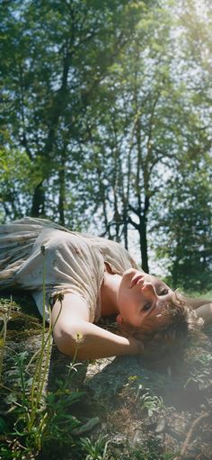 a woman laying on the ground in front of trees