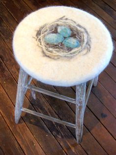 a small stool with a bird's nest on top of it, sitting on a wooden floor