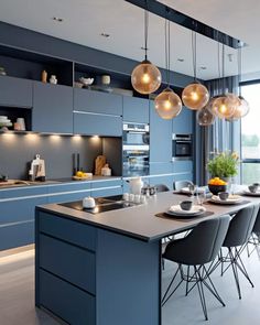 a kitchen with blue cabinets and lights hanging from the ceiling, along with gray chairs