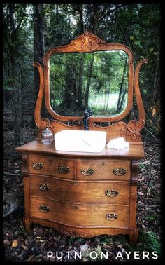 an old dresser with a mirror on it in the woods