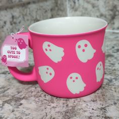 a pink cup with white ghost faces on it and a tag that says too cute to spook