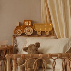 a teddy bear sitting on top of a bed next to a night stand with lights