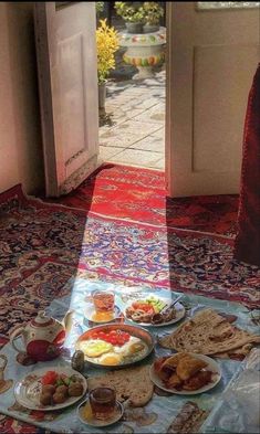 a table full of food sitting on top of a rug in front of an open door